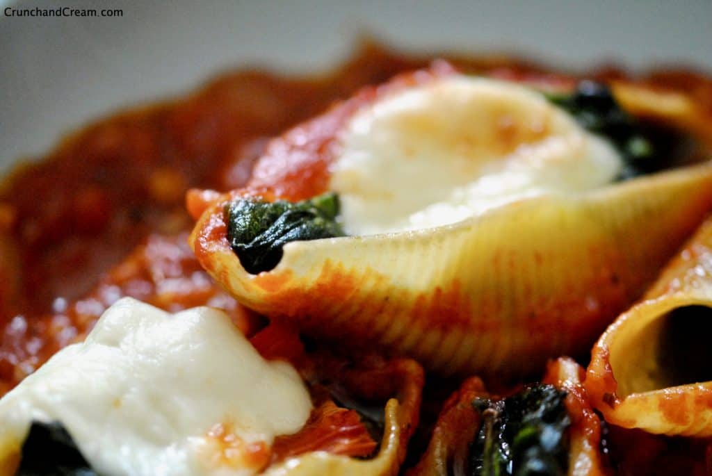 close-up view of stuffed pasta shells with spinach, pesto, peppers and mozzarella