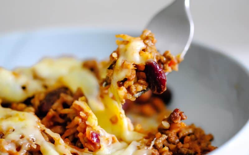 This cheesy Mexican rice bake is deliciously spicy. With rice, ground beef, chilli peppers and kidney beans baked in a spicy tomato sauce and topped with melty cheese, it really is a perfect comforting dinner!