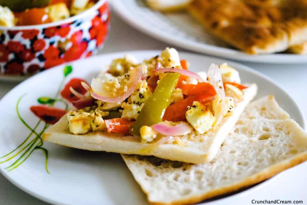 an open sandwich with pepper, tomato and onion roasted feta salad spread on it