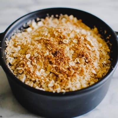 a small round dish of apple crumble with a golden, crispy topping