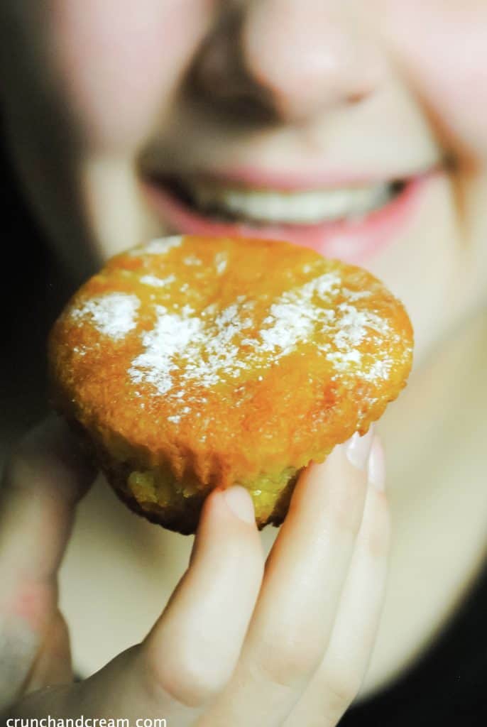 a young girl about to eat an eggless citrus olive oil cupcake dusted with icing sugar