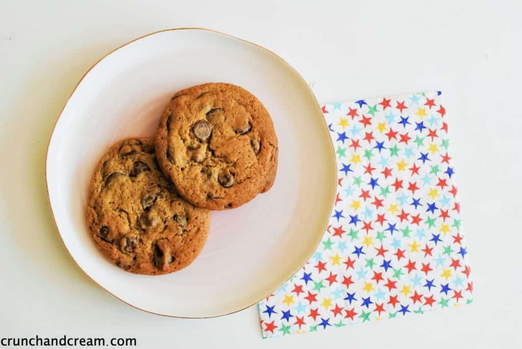 overhead of 2 chocolate chip cookies on a plate with a starry napkin